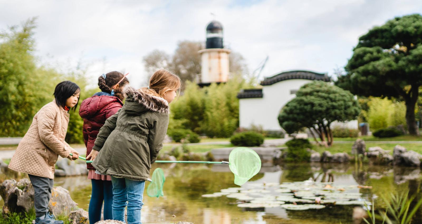 Kinder erkunden einen Teich bei einem Umweltbildungsangebot im Chinesischen Garten des IGA Park Rostock