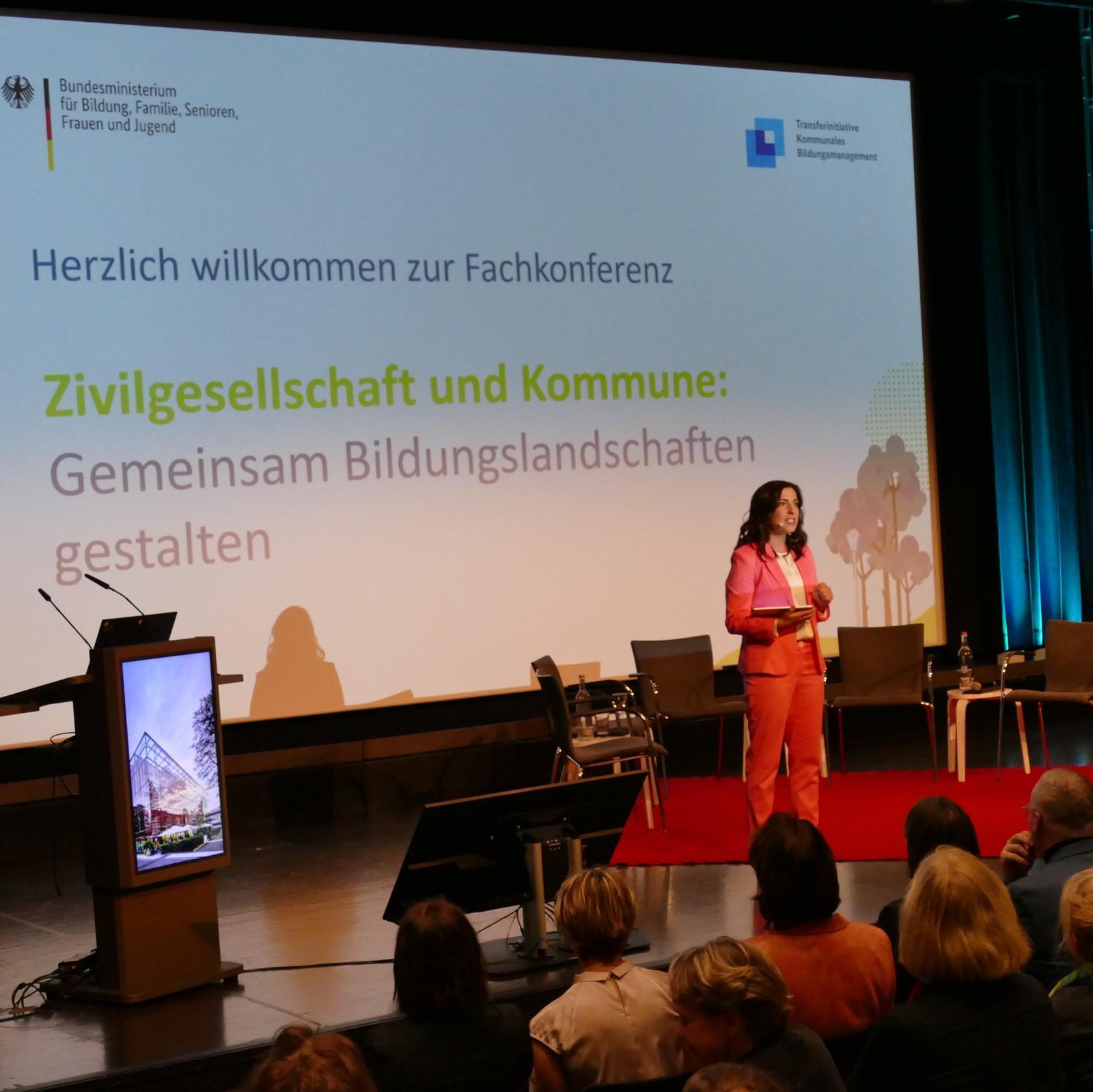 Foto von der Eröffnung der der Zivilgesellschaftstagung, mit Bühne, Moderatorin und Titel der Tagung im Hintergrund