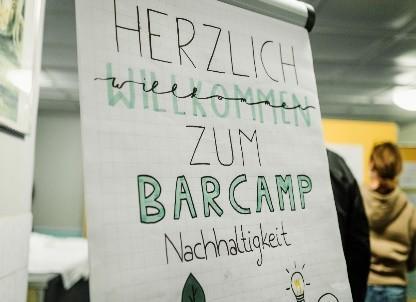 Foto von einem handgemalten FlipChartplakat, auf dem steht: Herzlich willkommen zum Barcamp Nachhaltigkeit